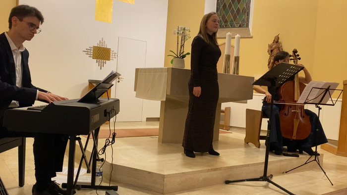 Musikere, der opfører en klassisk trio med klaver, cello og dirigent på scenen.