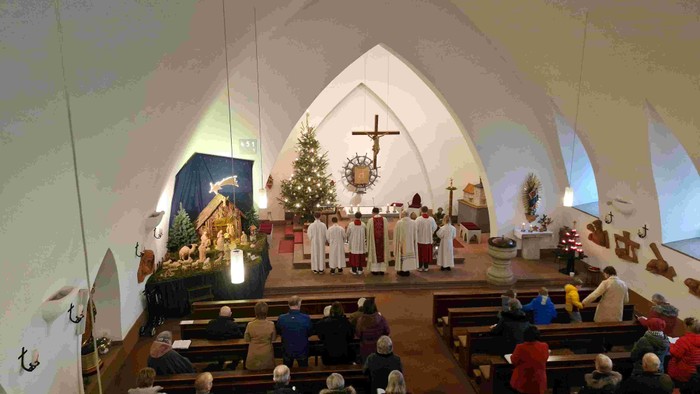 Ein friedvoller Gottesdienst mit Geistlichen in weißen Gewändern, die eine Zeremonie für eine aufmerksame Gemeinde abhalten.