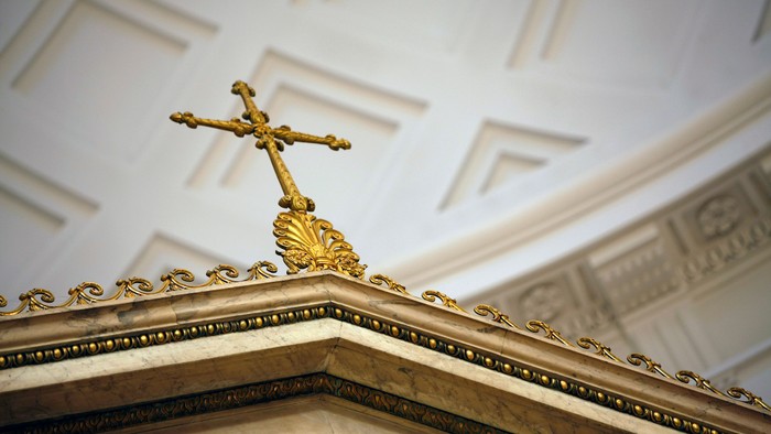 Forgyldt, prægtigt kors oven på et indviklet dekoreret loft og alterkant.