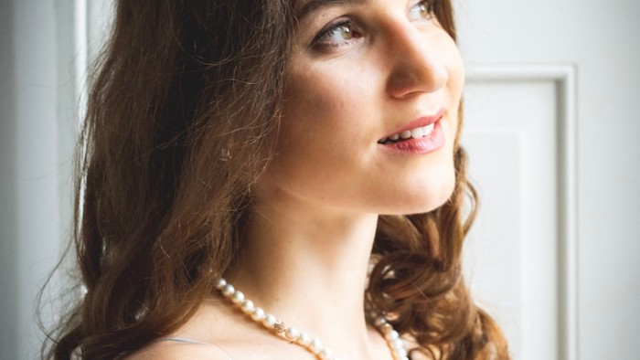 Eine Frau mit dunklen Haaren und Perlenkette aus dem Seitenprofil gesehen