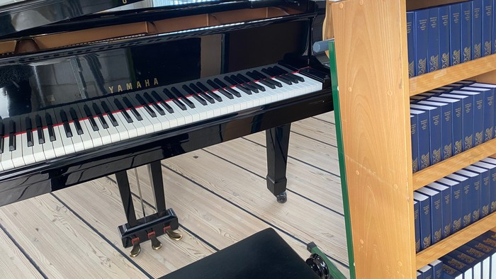 Sort Yamaha-flygel ved træreol med blå bøger