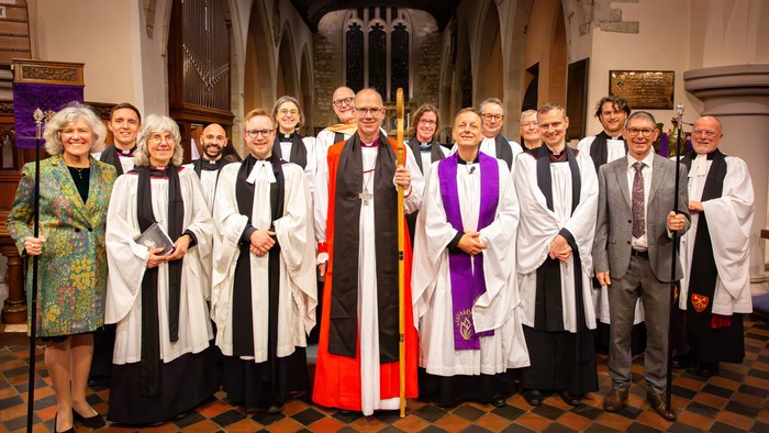 Group of clergy and choir members in ceremonial robes posing together inside a church.