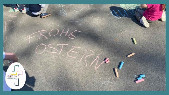 Die Kinder schrieben „Frohe Ostern“ mit Kreide auf den Gehweg, während bunte Kreidestücke herumlagen.