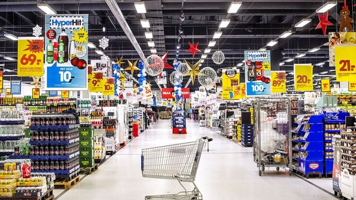 Veloplyst supermarkedsgang med indkøbsvogn, fyldt med forskellige nedsatte varer og festlige dekorationer.