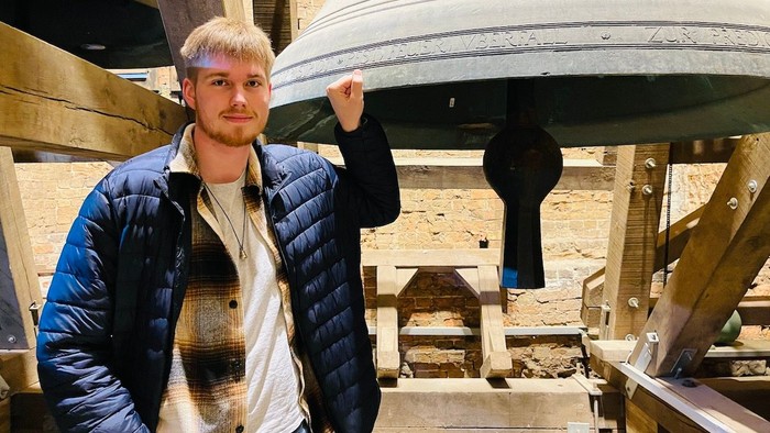 Mika Pagels steht an einer Glocke im Turm von St. Marien.