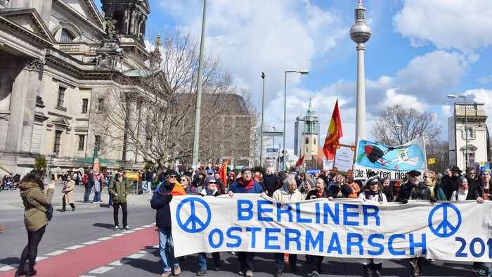 Ein Demonstrationszug mit einem großen Banner "Berliner Ostermarsch 2016" vor dem Berliner Fernsehturm.