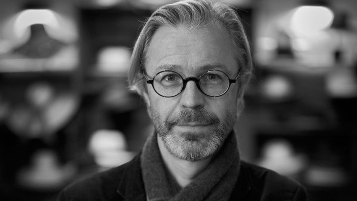 Schwarz-Weiß-Portrait von Kris Lauwerys, ein mittelalter Mann mit Bart, Brille, Mantel und Schal.