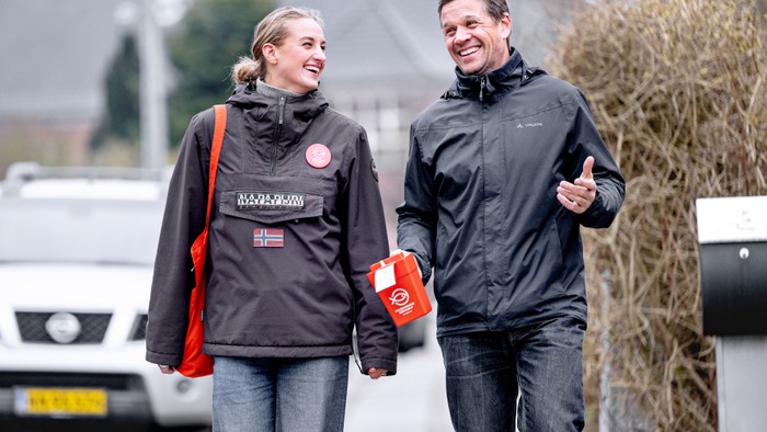 En mand og en kvinde går sammen på en vej, begge med rygbags og lykkelige udsigt.