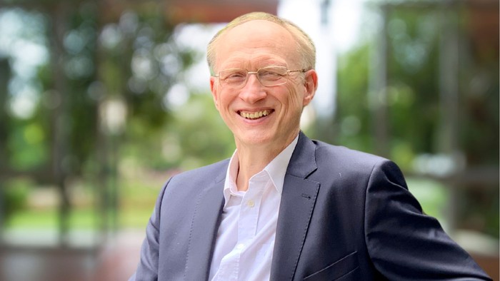 Mit unscharfem Hintergrund Josef Groß in Hemd und blauem Anzug