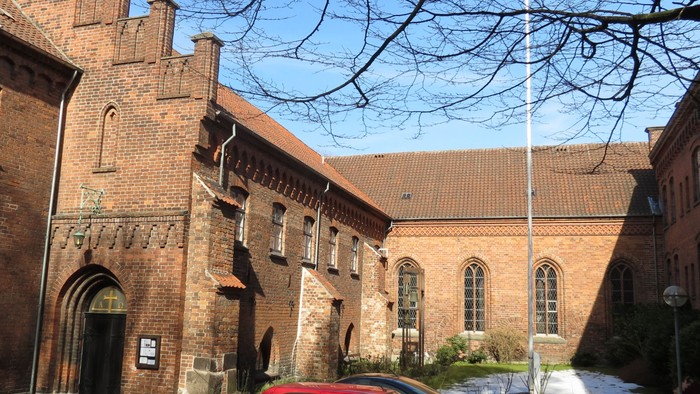 Gamle murstensbygning med biler foran