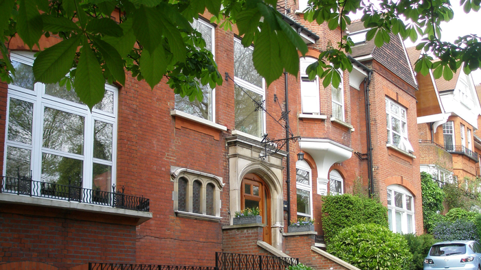 En rød murstensbygning med store vinduer og grønne planter.