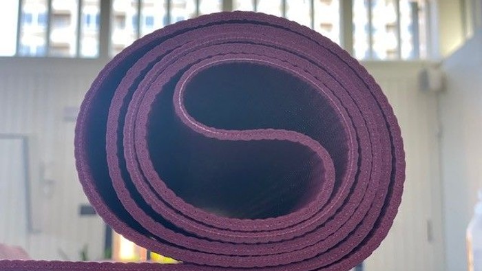 Rollede yoga-mat i mørke rød og blå farver.