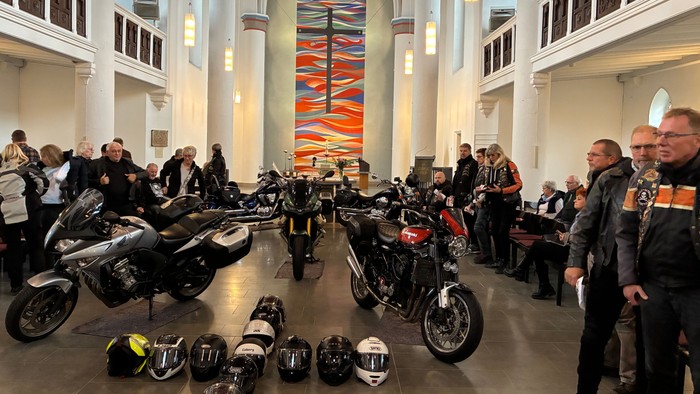 Motorradbegeisterte versammeln sich mit ihren Bikes und Helmen in einer geräumigen, gewölbten Halle.