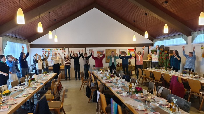 Die Gruppe feiert fröhlich auf einem festlichen Bankett mit erhobenen Armen und geschmückten Tischen.