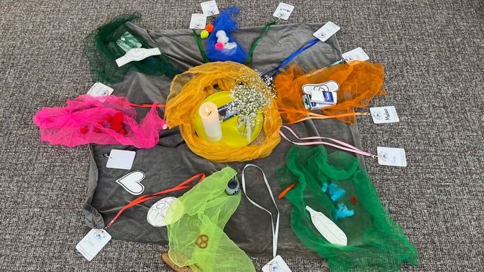 Bunte Tücher liegen im Kreis um eine Kerze herum