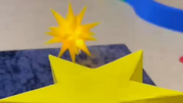 Zwei Kerzenhalter in Sternform liegen auf einer Blauen Oberfläche, plus Text: Und zwar mit diesem sprechenden Wackelstern in den Händen.