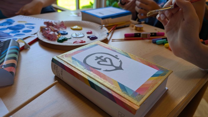 Ein Kind malt an einem Buch mit bunten Farben an einem Tisch