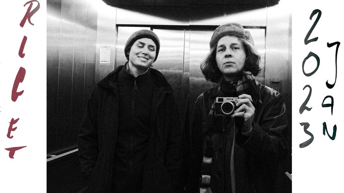 Sort-hvid selfie af to personer i en elevator, der holder et vintage-kamera, dateret 2013.