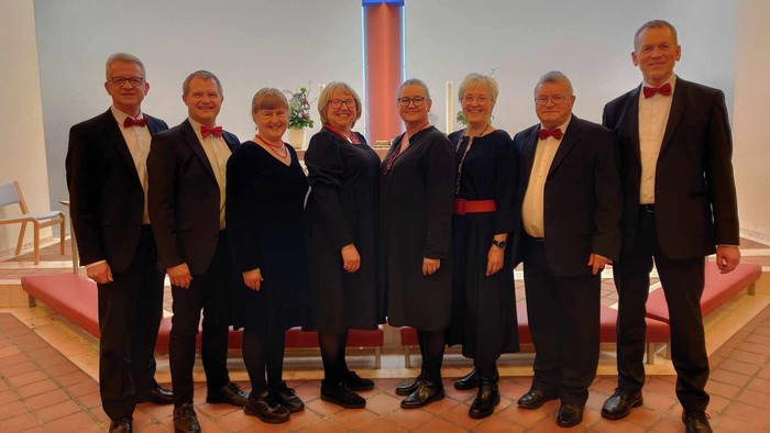 Gruppe, der poser formelt sammen i en kirke, iført sort tøj og butterfly.