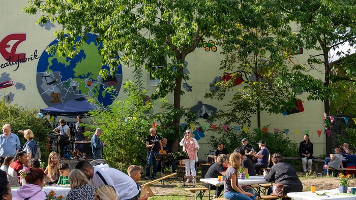 Eine Gruppe von Menschen feiert vor einem Gebäude mit einem bunten Wandgemälde.