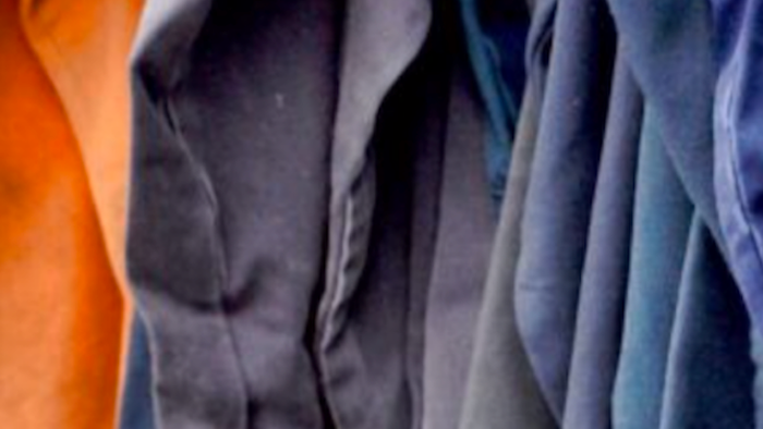 Nahaufnahme gefalteter Stoffmuster in Orange-, Grau- und Blautönen.