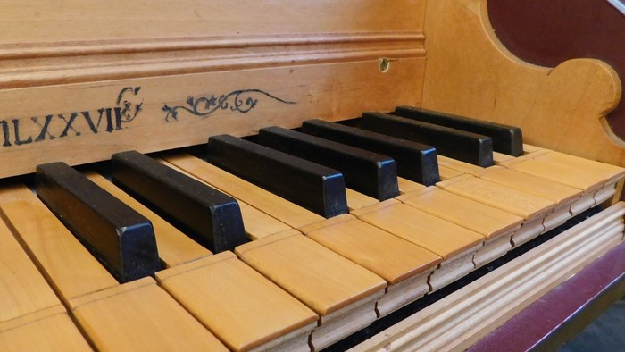 Nahaufnahme einer antiken Holzklaviatur mit verzierten Details und schwarzen und weißen Tasten.