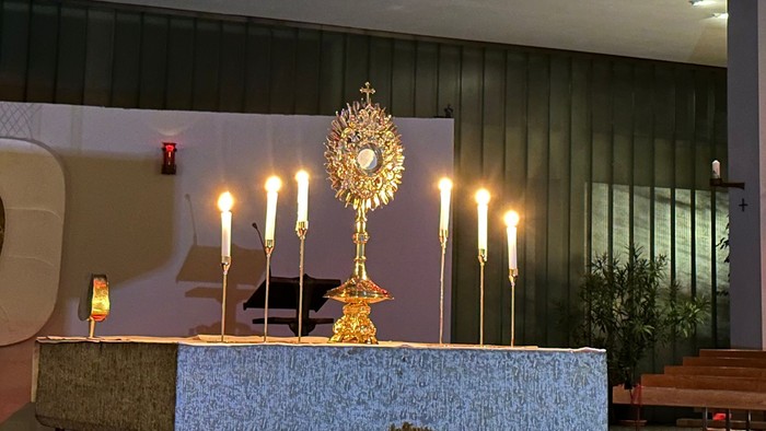 Innenraum einer Kirche mit Altarraum, Kerzen und Blumen