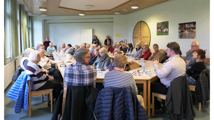 Gruppe von Menschen, die sich um Tische versammelt haben und sich in Gespräche und Aktivitäten vertiefen.