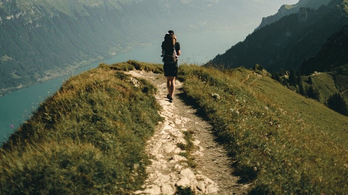 Ein Wanderer auf einem Kammweg oberhalb eines Bergsees