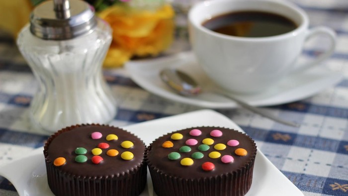 Bild von einer Kaffeetasse und zwei Muffins mit Schokolinsen
