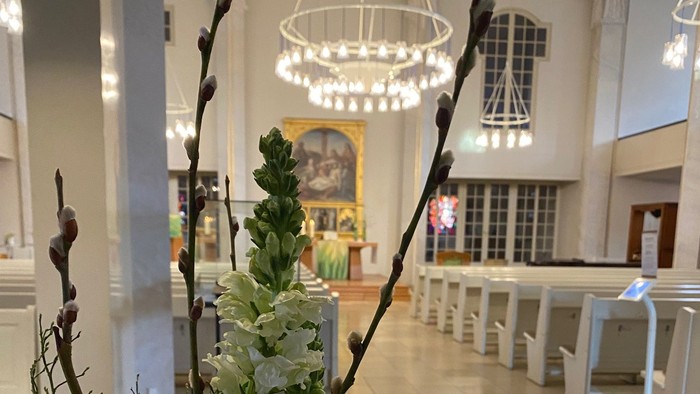 Elegante Blumenarrangement in der modernen Kirchenlobby mit einer Zeitschriftenauslage auf einem Tisch.