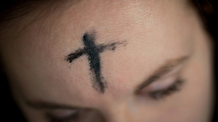 Nahaufnahme einer Stirn mit einem temporären Kreuz-Tattoo.