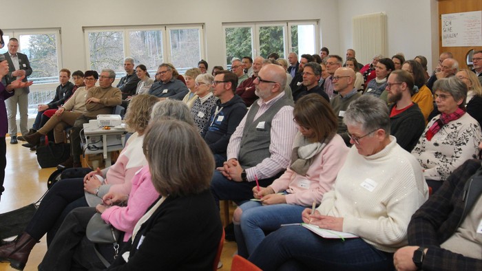 Eine vielfältige Gruppe hört aufmerksam einem Redner bei einer Indoor-Gemeinschaftsveranstaltung oder -besprechung zu.