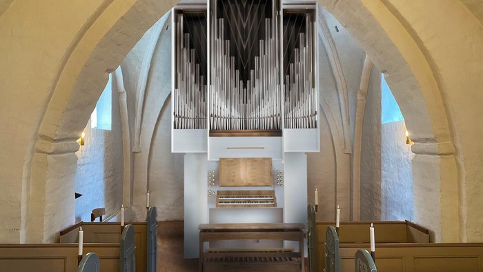 Et stort pibeorgel står fremtrædende i en historisk kirkes hvælvede indre med træbænke nedenunder.