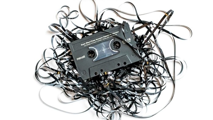 Ein wirres Durcheinander aus Audiokassetten und Kabeln, das eine einzelne Kassette umgibt.