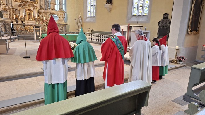 Geistliche in zeremoniellen Gewändern versammeln sich in einer Kirche für eine religiöse Prozession oder Zeremonie.