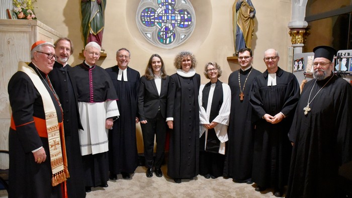 Gruppe af gejstlige og religiøse personer, der poser formelt inde i en kirke med religiøse dekorationer.
