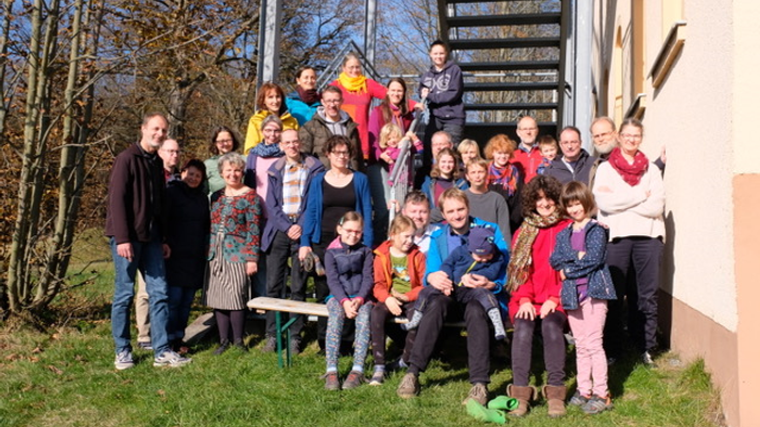 Eine Gruppe von Menschen posiert vor einem Haus mit Treppe