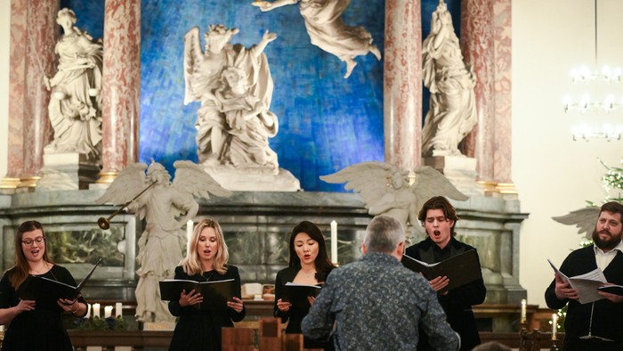 En kor sang i kirke med storslået altertavle.