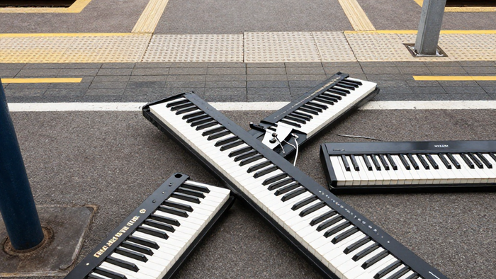 Zwei tragbare Keyboards, die sich auf einem Bahnsteigpflaster kreuzten.