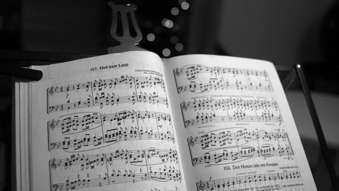 Man erkennt ein Notenblatt vor dunklem Hintergrund. 