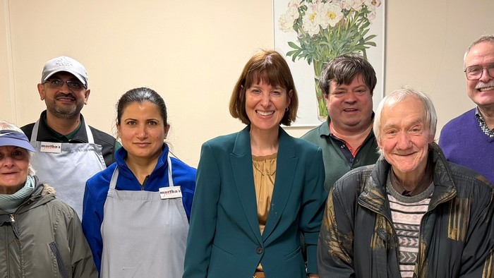 Gruppe von acht Personen, die drinnen bei einer formellen und zwanglosen Zusammenkunft posieren.