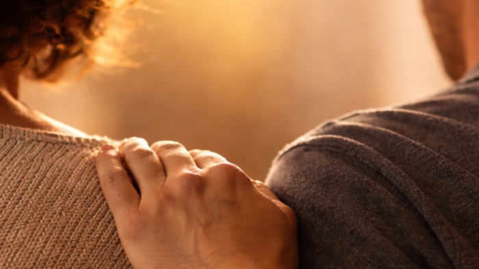 Ein Mensch berührt mit der Schulter die Schulter eines anderen Menschen.