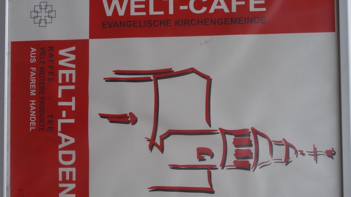 Das Schild zeigt das Welt-Café mit einem skizzierten Kaffee.