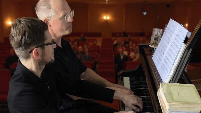 Zwei Pianisten spielen auf einem Flügel.