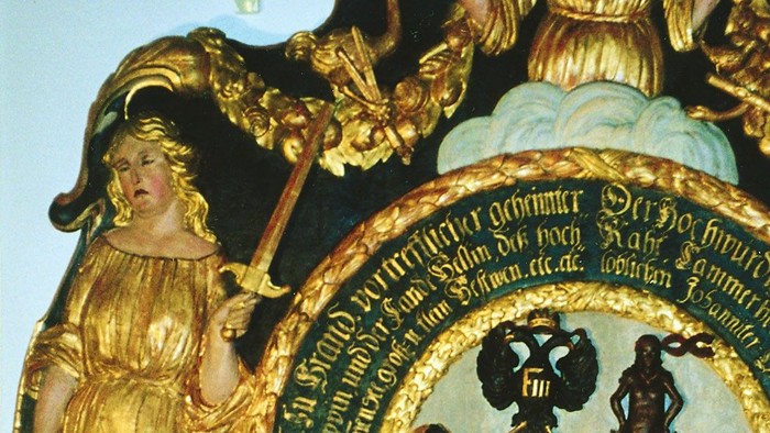 Verzierter heraldischer Schild, flankiert von Figuren, gekrönte Helmzier und Putten mit aufwendigen Gold- und Blauverzierungen.