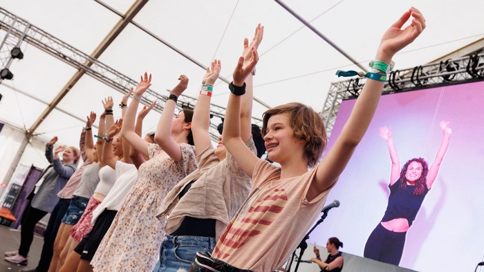 Eine Gruppe von Menschen feiert auf einer Bühne, die Arme hoch und glücklich.