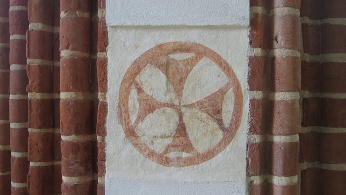 En hvidsten med et rødt symbol på en mur af røde teglsten