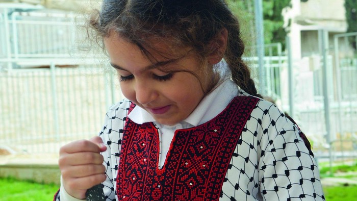 Ein junges Mädchen pflanzt Samen mit einer Botschaft, die Hoffnung und Nächstenliebe für Palästina fördert.