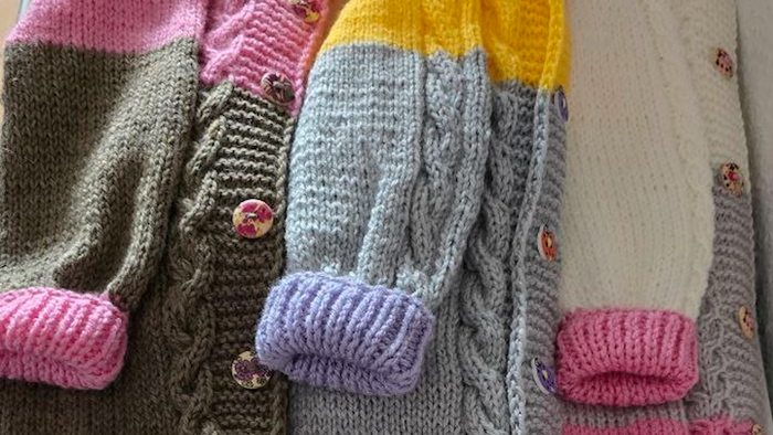 Bunte gestrickte Handschuhe mit dekorativen Knöpfen und kontrastierenden Bündchen in verschiedenen Pastelltönen.